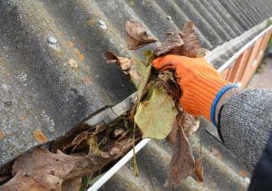 bigstock-Roofer-Hand-Cleaning-Rain-Gutt-327489319-300x211